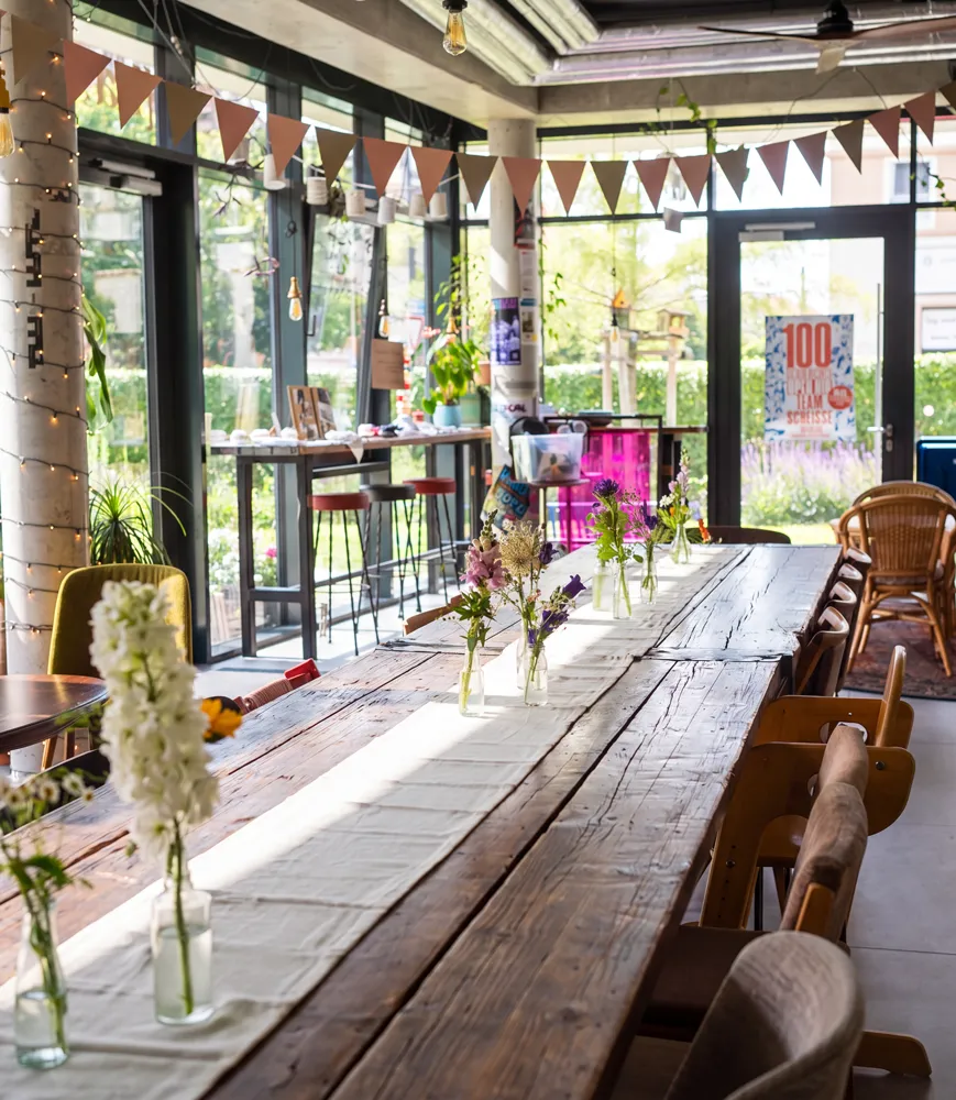 Lange festlich gedeckte Tafel mit Blumen und Wimpelkette im kate Café als Partyraum